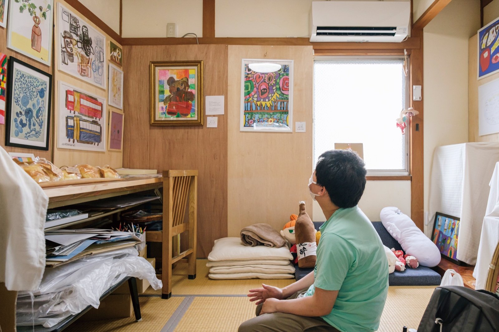 アトリエの壁一面に並んだ作品と、それを眺めるShiroiToのメンバー